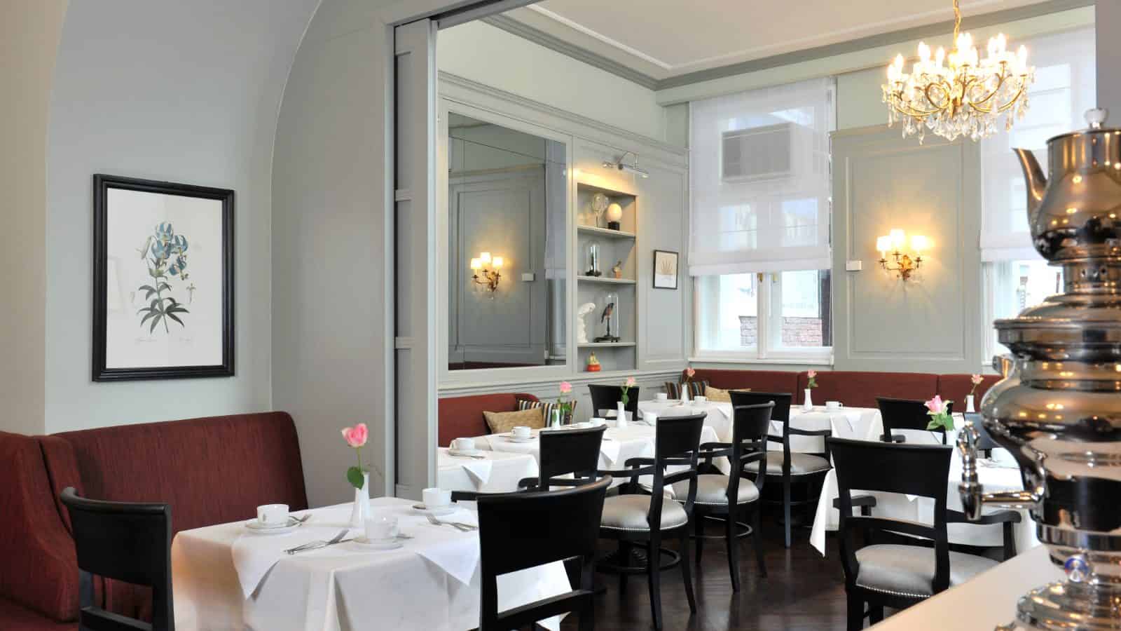 Salon des Hotel Kärntnerhof mit gedeckten Tischen, Luster und Samowar