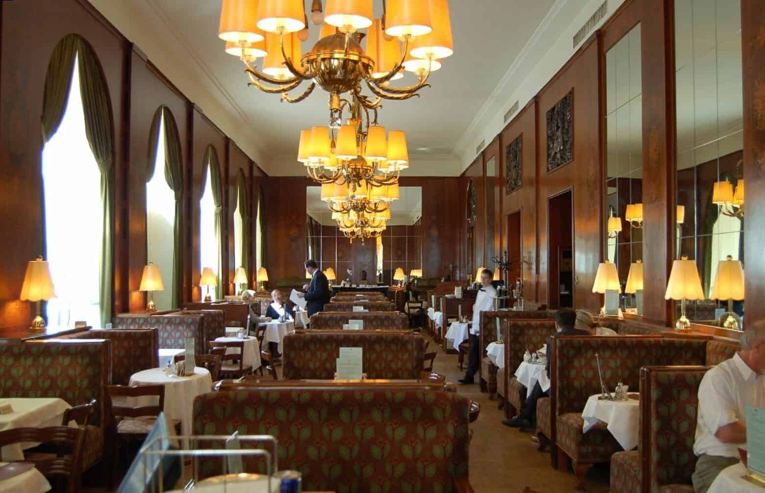 Langgestreckter Gastraum des Café Landtmann mit Lustern und gedeckten Tischen