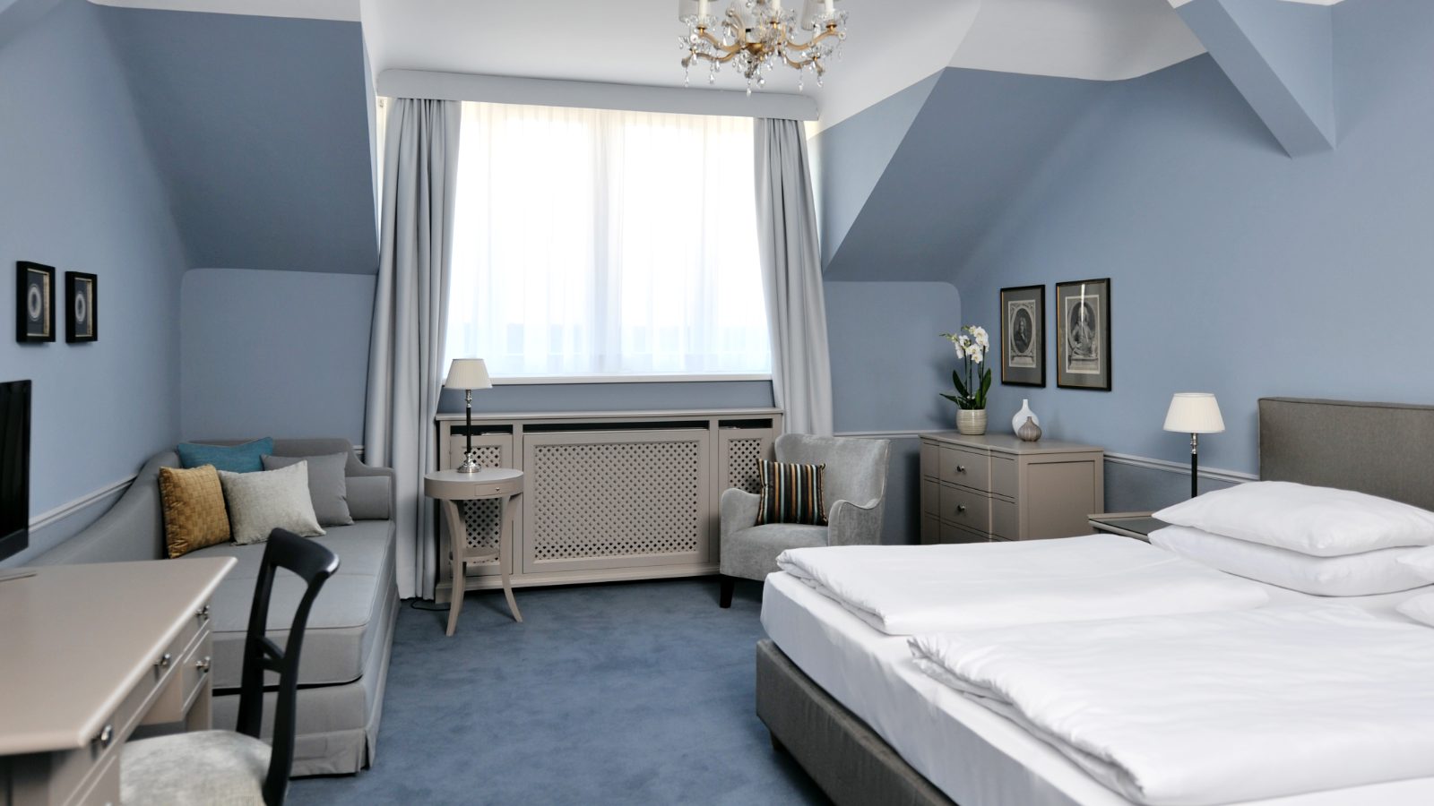 Dreibettzimmer im Hotel Kärntnerhof unter der Dachschräge mit Doppelbett, zusätzlichem Einzelbett, Luster und Schreibtisch