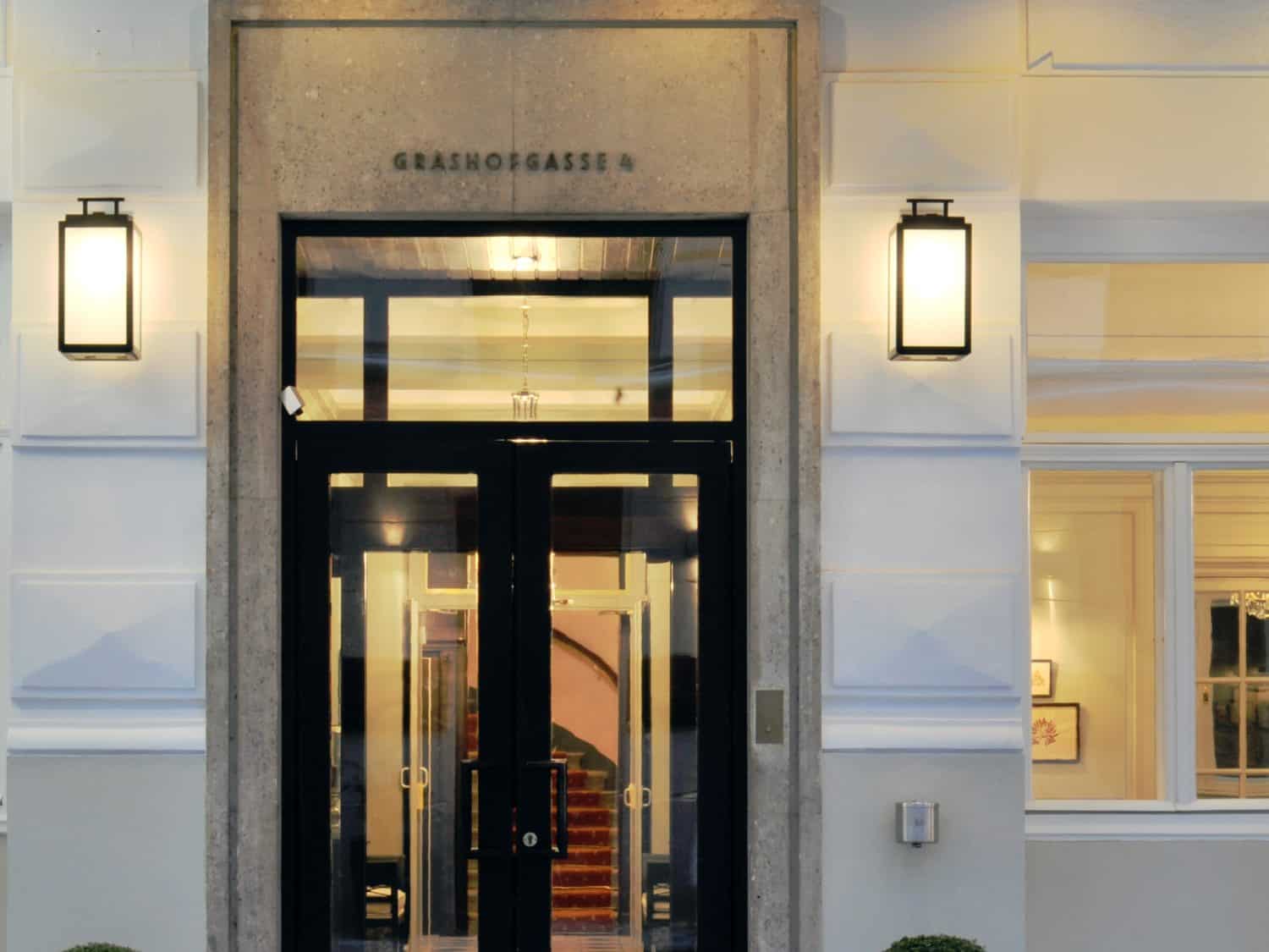 Eingang des Hotel Kärntnerhof mit der eingravierten Adresse Grashofgasse 4 über der schwarzen Tür, flankiert von zwei Laternen