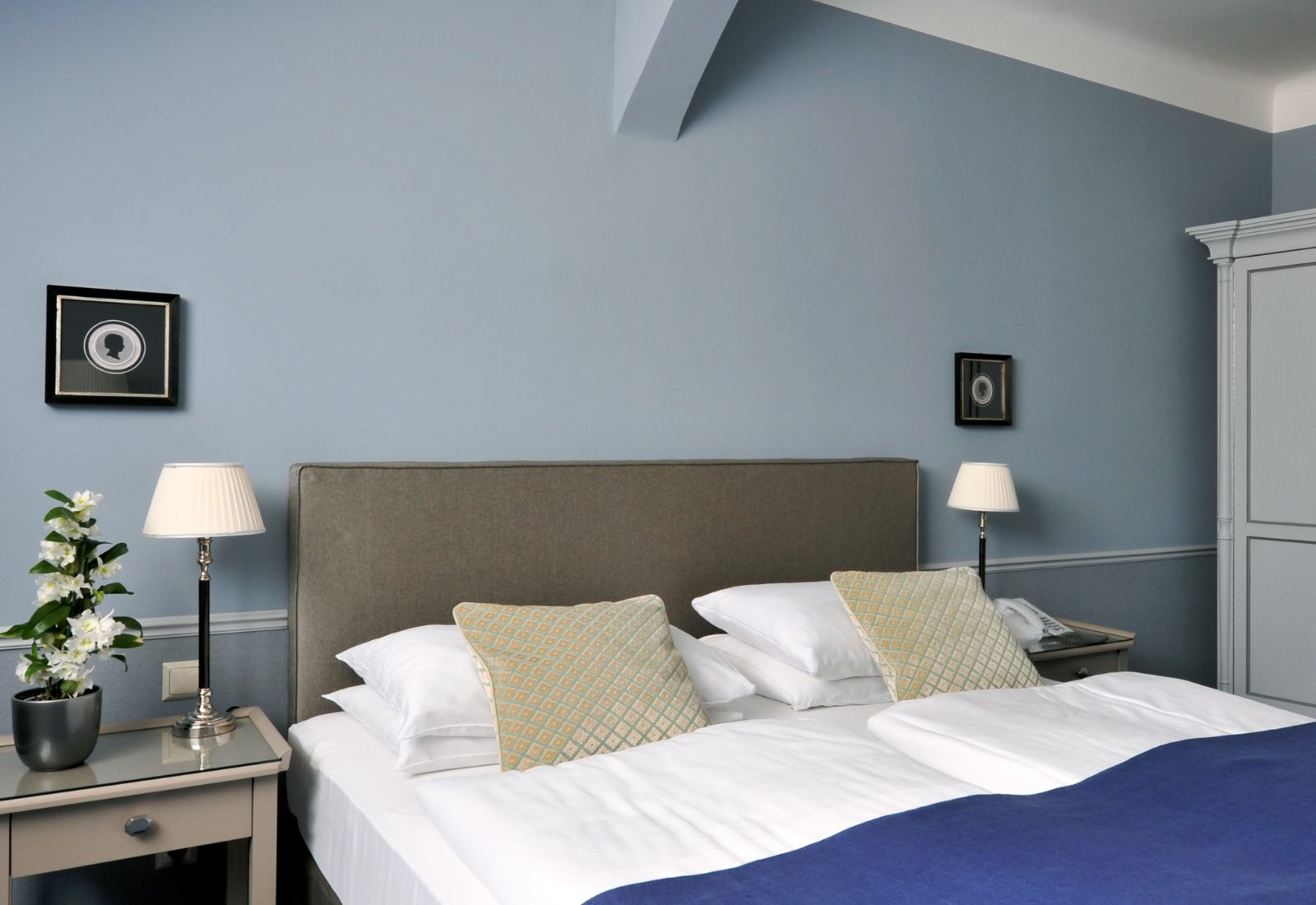 Schlafbereich einer Suite im Hotel Kärntnerhof mit gepolstertem Kopfteil unter der Dachschräge
