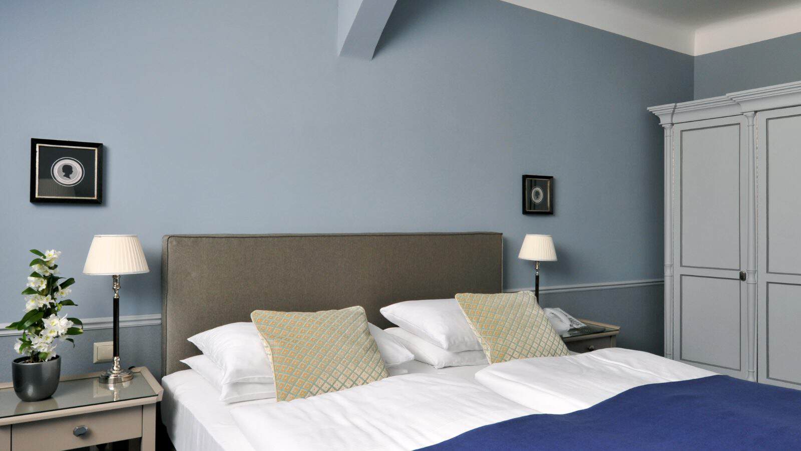 Schlafbereich einer Suite im Hotel Kärntnerhof unter der Dachschräge mit blauer Tagesdecke