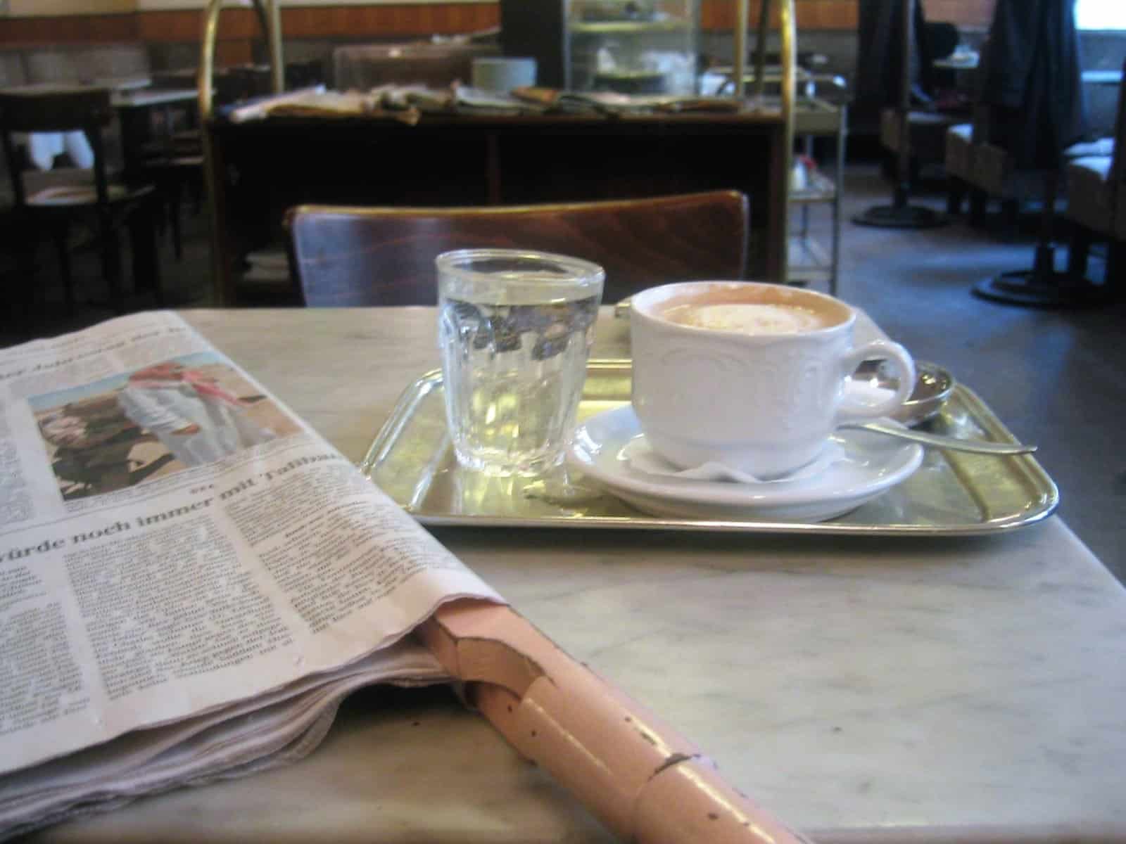 Melange mit Wasserglas auf einer aufgeschlagenen Zeitung im Café Bräunerhof