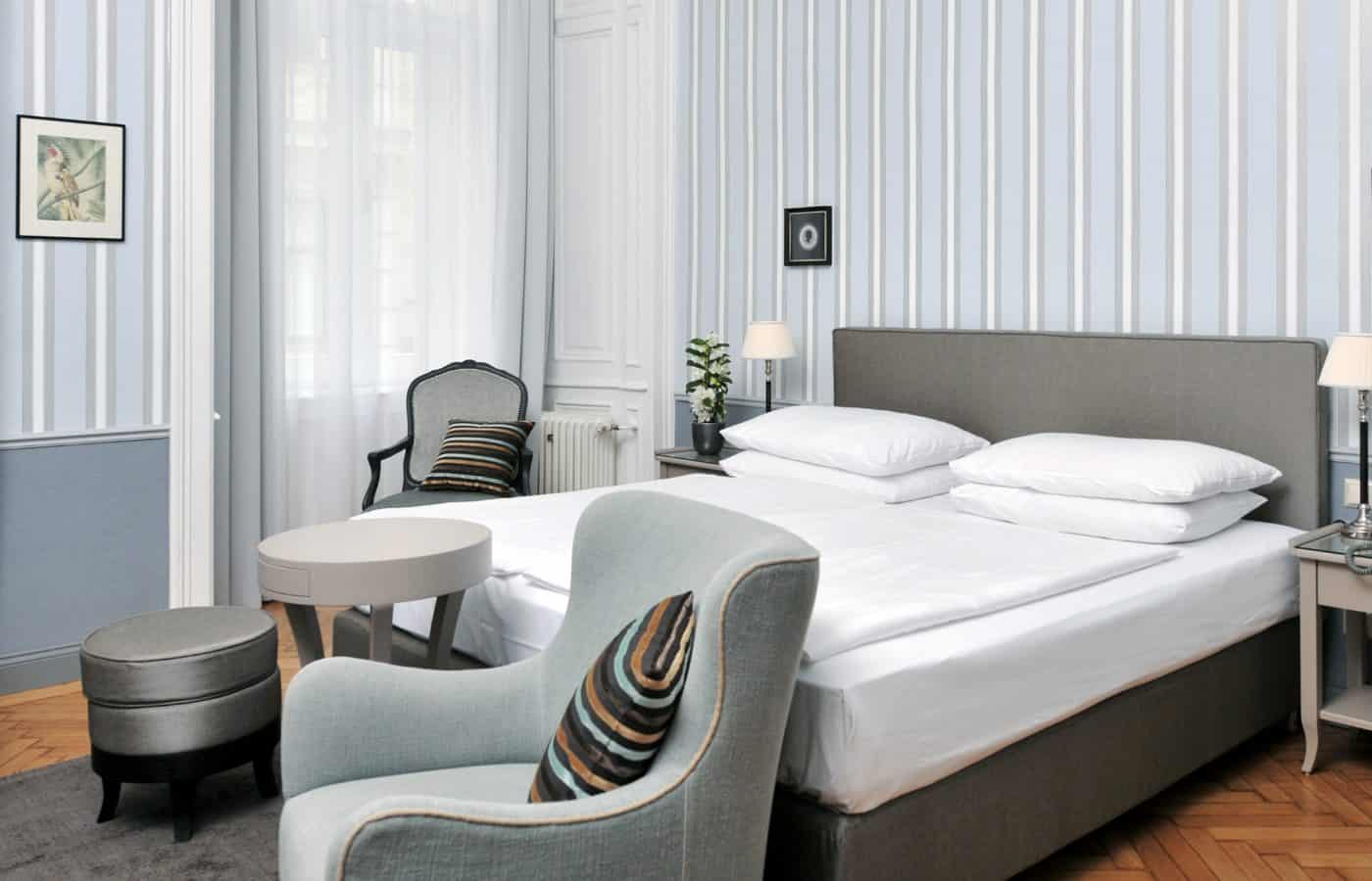 Großes Doppelzimmer im Hotel Kärntnerhof mit hellblauer Streifentapete und Sessel