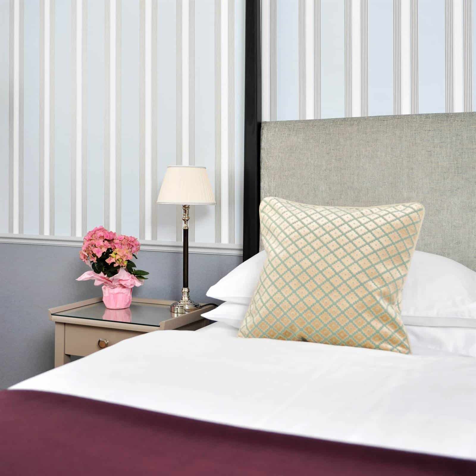 Bett in der Christiane Hörbiger Suite des Hotel Kärntnerhof mit rosa Blumen auf dem Nachttisch