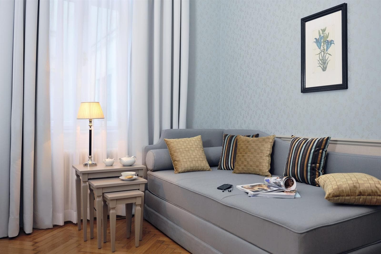 Dreibettzimmer im Hotel Kärntnerhof mit Bank am Bettende und gerahmtem Bild an der Wand