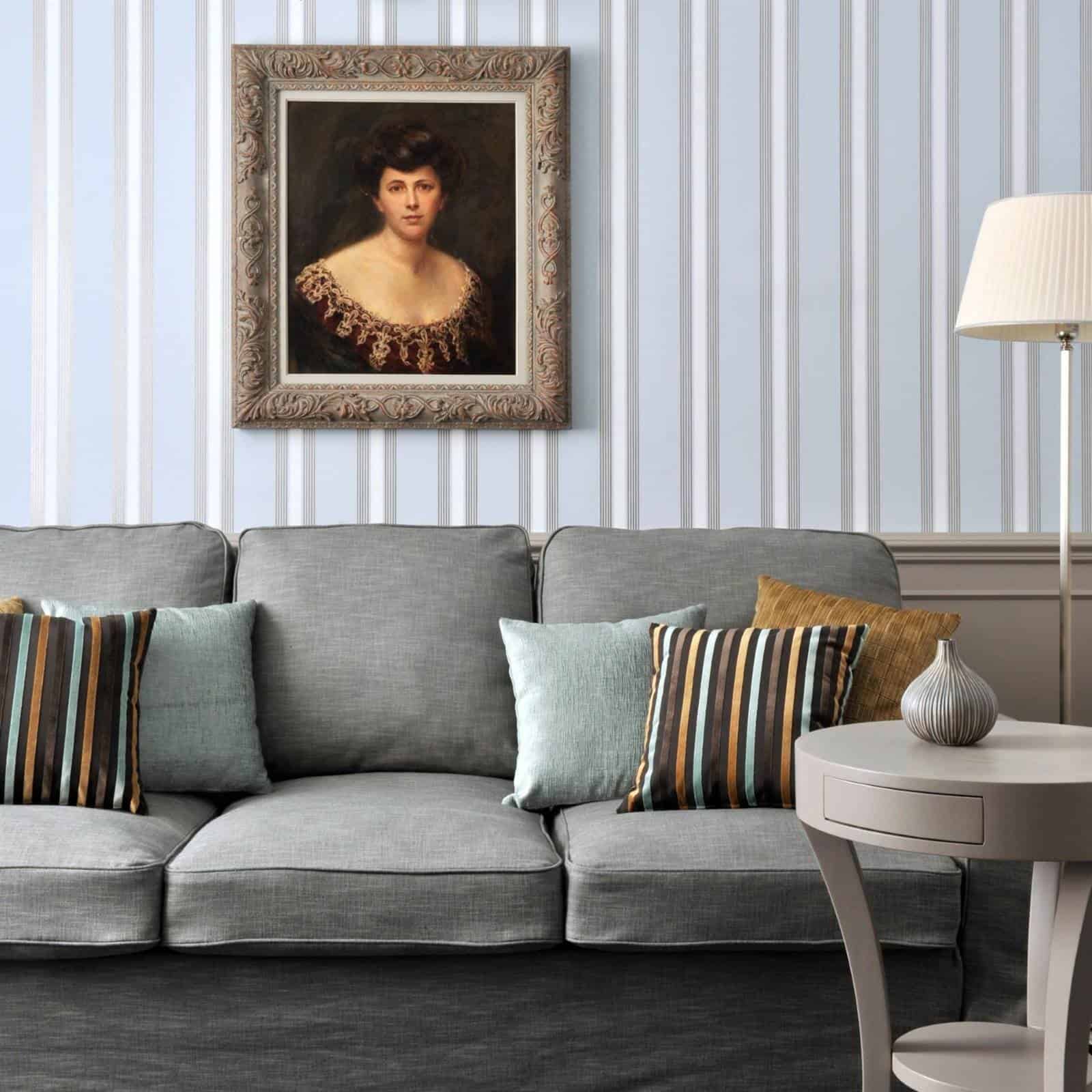 Madame Rosa Suite im Hotel Kärntnerhof: graues Sofa mit Streifenkissen unter einem Frauenporträt im Goldrahmen